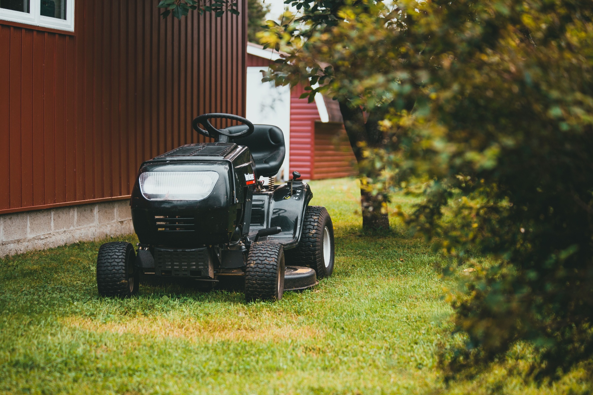 Professional riding mower on a freshly cut lawn next to a home